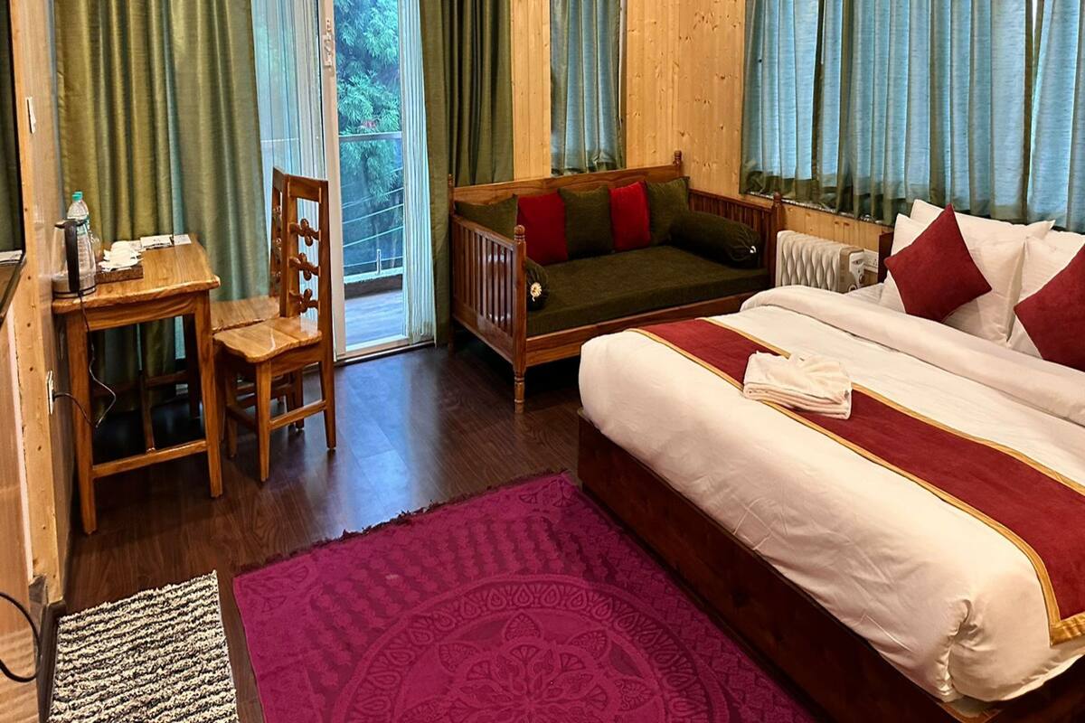 A wooden cabin-style room with a bed, a sofa, a desk, and a chair.