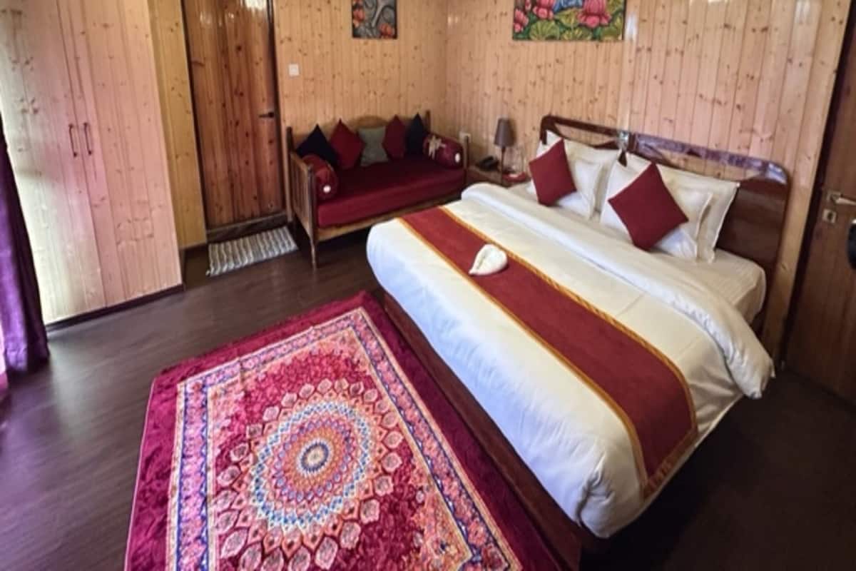 A wooden-paneled room with a large bed, a sofa, and a painting on the wall.