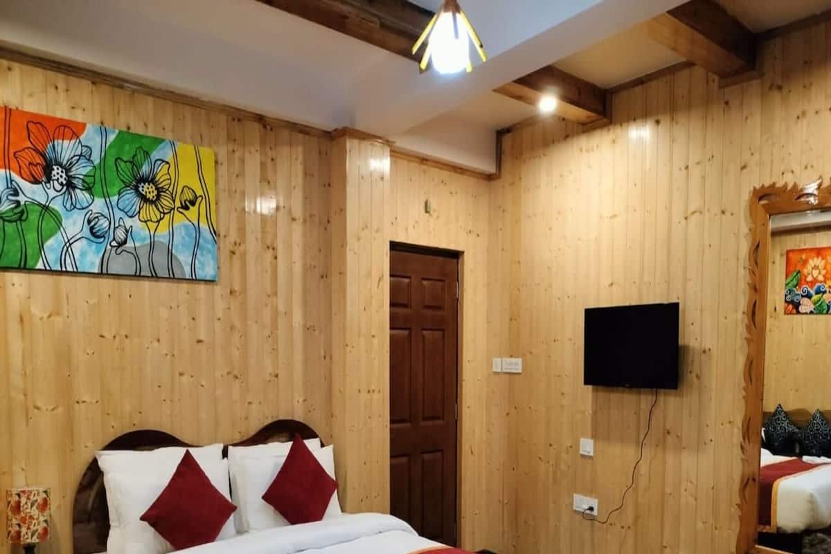 A wooden-paneled room with a bed, a TV, and a painting on the wall.