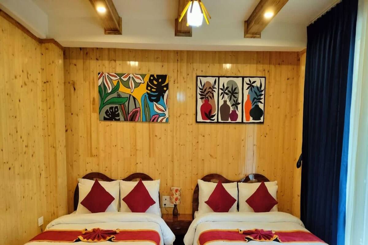 A double room with two beds, wooden walls, and a blue patterned rug.