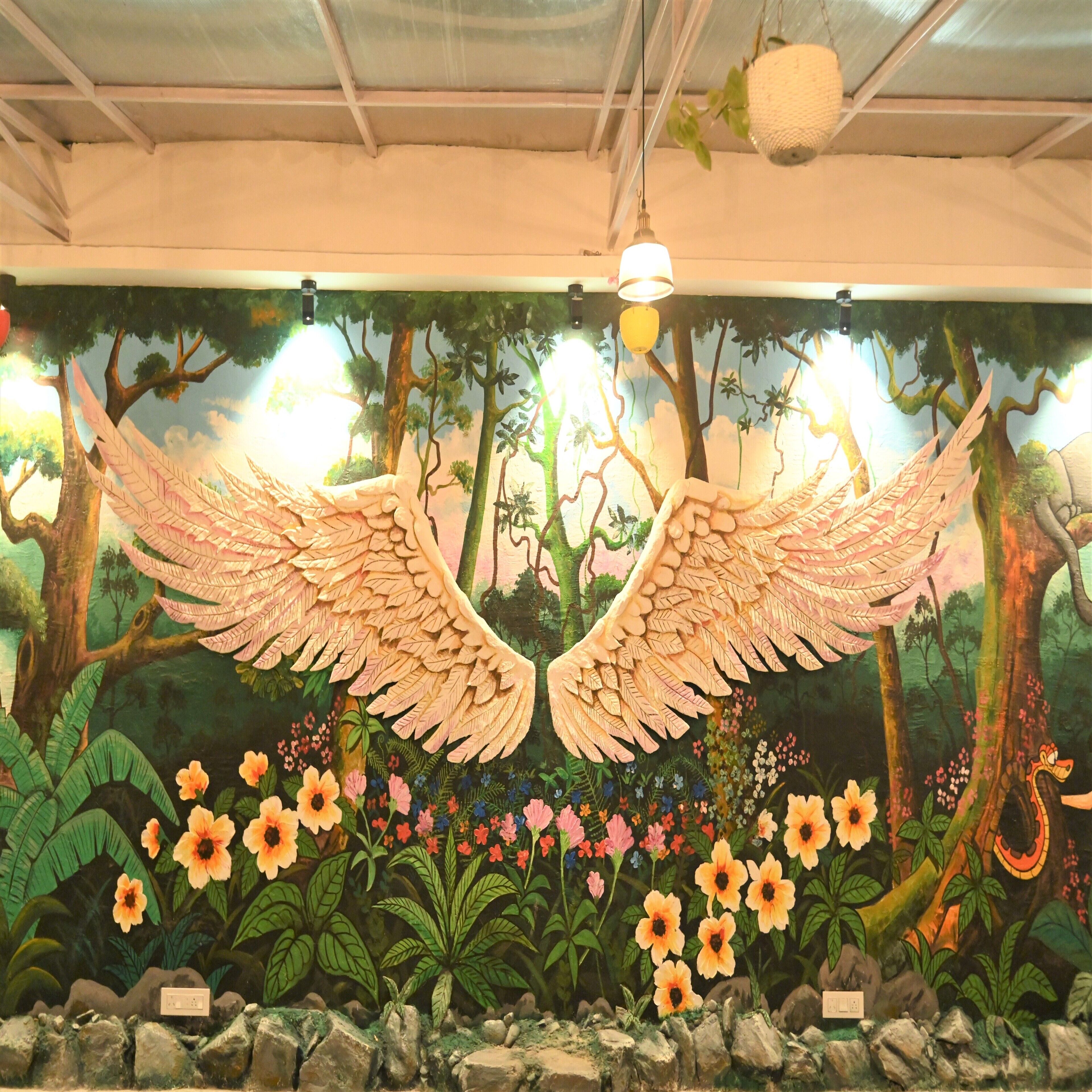 Un murale raffigura una grande figura alata e una scena di foresta.