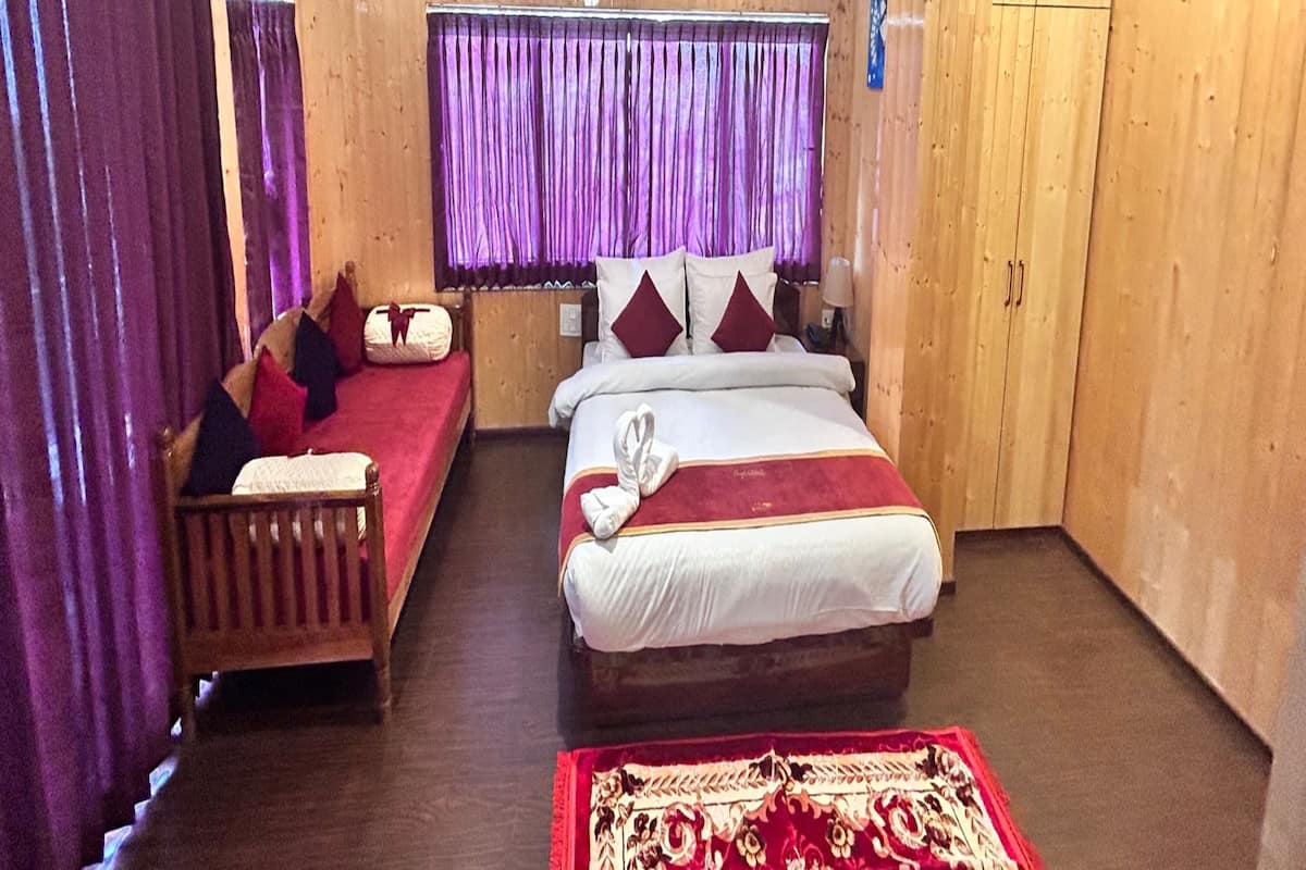 A room with two beds, wooden walls, a purple curtain, and a red carpet.