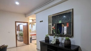 A hallway with a black console table, potted plants, a large mirror, and a door leading to another room. - The Altruist Bellandur ORR Hotel (Bengaluru)