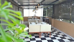 A restaurant with a checkered floor, a table set for two, and hanging pendant lights. - The Altruist Bellandur ORR Hotel (Bengaluru)