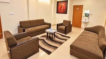 A living room with a sofa set, armchairs, a coffee table, and a rug.