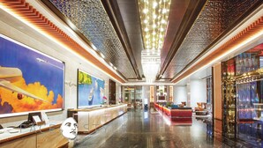 A modern hotel lobby with a reception desk, seating area, and a large window with a view of a red car. - THE FACE Style Hotel (Kuala Lumpur)