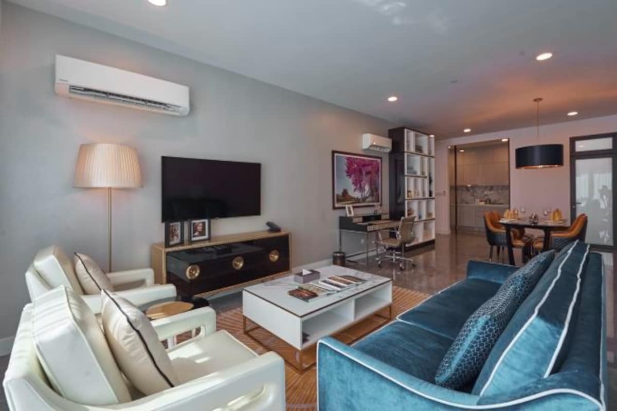 A modern living room with a sofa, a coffee table, a TV, and a bookshelf.