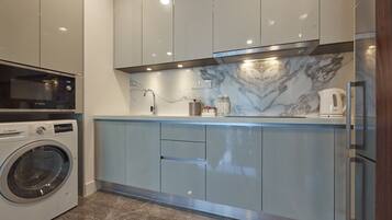 A modern kitchen with a built-in washing machine, marble backsplash, and stainless steel appliances.