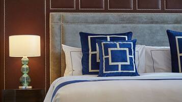 Une chambre d’hôtel avec une tête de lit capitonnée, une lampe de chevet et des oreillers à motifs bleus et blancs.