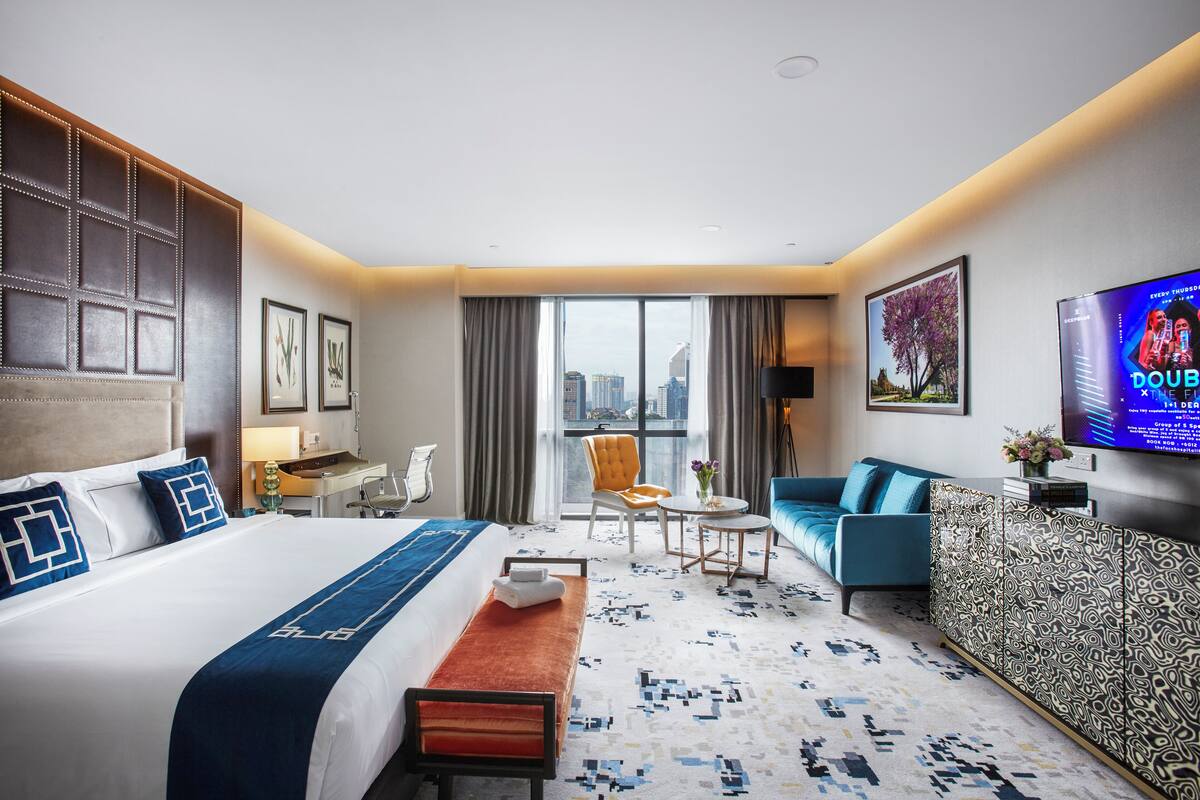 A hotel room with a large bed, a sofa, a desk, and a TV.