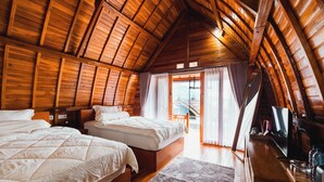 Acogedor dormitorio en el ático con dos camas, vigas de madera y vistas a un balcón.