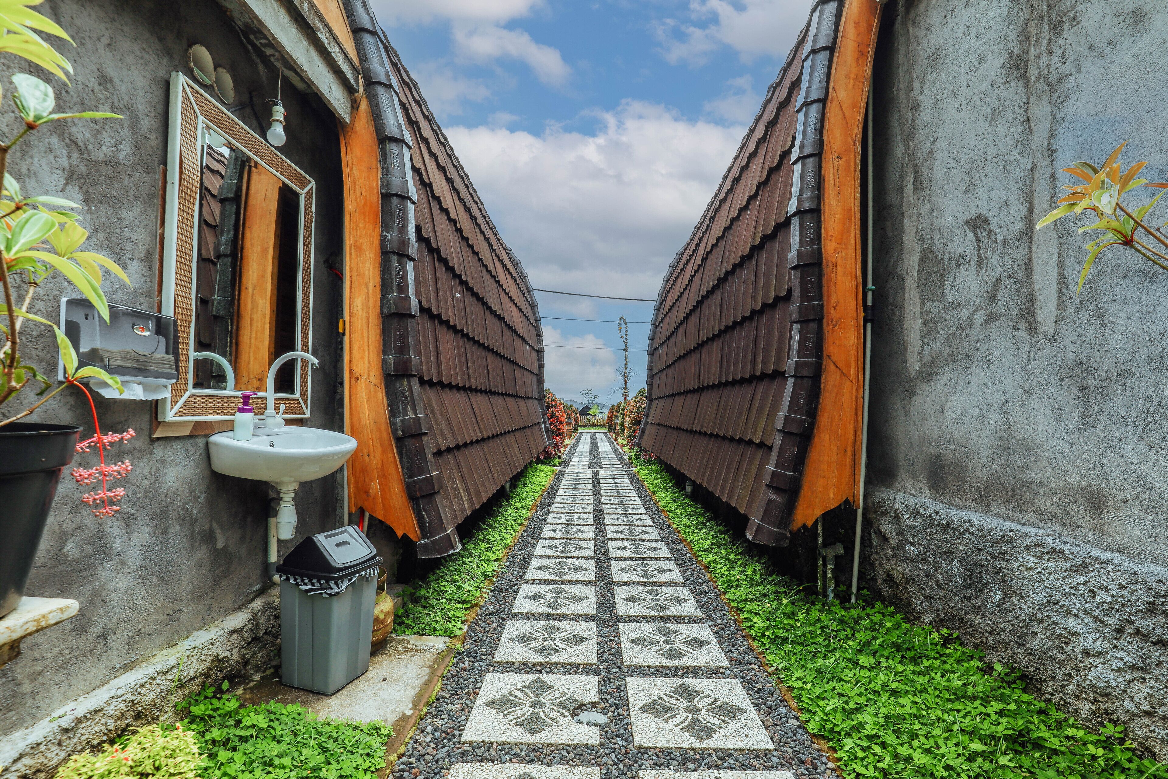 A narrow pathway flanked by two buildings with corrugated metal roofs, leading to a central point.