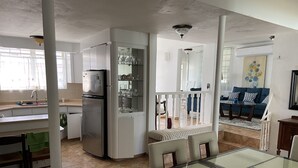 A modern kitchen with a refrigerator, sink, and dining area with a glass table. - Beach Getaway (Punta Santiago ,Humacao)
