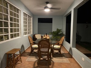 Uma área de refeições com uma mesa redonda, cadeiras de vime e um ventilador de teto.