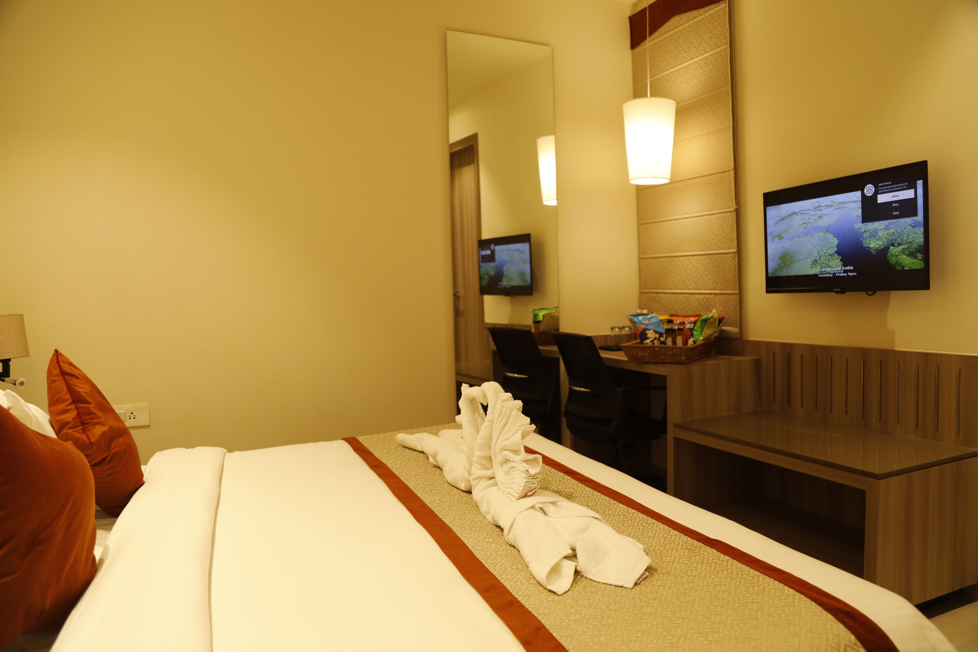 A hotel room with a bed, a desk, a TV, and a seating area.