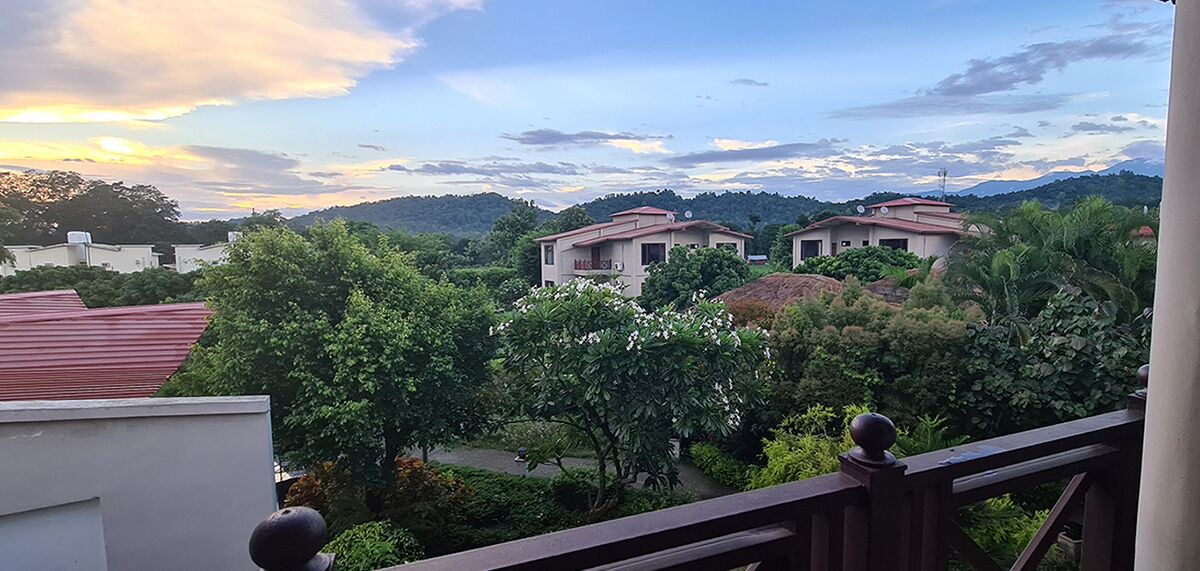 A residential area with houses surrounded by greenery and hills in the background.