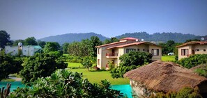 A resort with multiple buildings, a swimming pool, and lush greenery. - Alaya resort Corbett (Ramnagar)