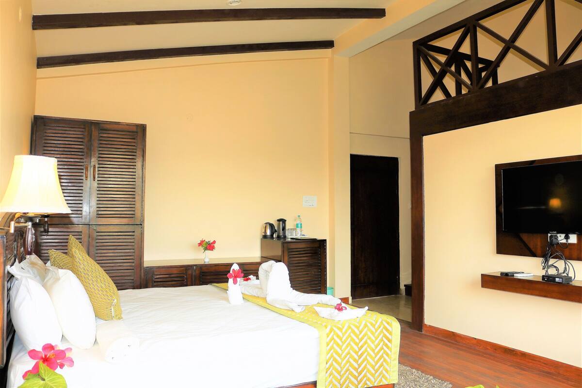 A hotel room with a bed, a television, a desk, and a lamp.