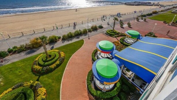 A coastal hotel with a beach view, a landscaped garden, and a blue-roofed building. - Studio unit at Boardwalk Villas  (Virginia Beach)