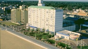 A multi-story hotel with a central courtyard, surrounded by a parking lot and a beach. - Studio unit at Boardwalk Villas  (Virginia Beach)