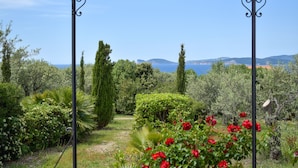 En trädgård med en pergola, olika växter och utsikt över havet och kullarna.
