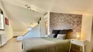 A bedroom with a bed, a nightstand, a wall-mounted headboard, a window, and a staircase. - Unit 1291248 - SWEET HOME OF THE VINES - (Rully)