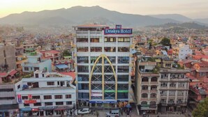 Un edificio de varios pisos con un letrero llamativo del Hotel Drishya.