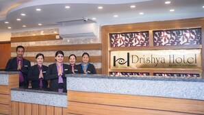 Una recepción en el Hotel Drishya con un panel de madera y un letrero.