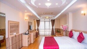 Una habitación de hotel con una cama grande, un escritorio, una silla y un armario.