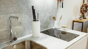 Eine moderne Küche mit Spüle aus Edelstahl, eingebautem Herd und einer Marmor-Spritzschutzwand.