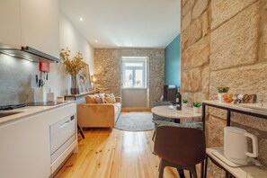 A modern kitchen with a stone wall, a dining area with a round table, and a cozy seating arrangement. - Oporto Pool Apartment by Vacationy (Porto)