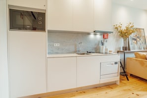 A modern kitchen with white cabinets, a built-in oven, and a sink.