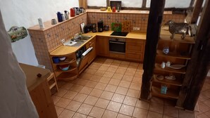 A kitchen with wooden cabinets, a sink, a stove, and various kitchen utensils. - Vacation cottage Haus Hellhake (Sundern (Sauerland))