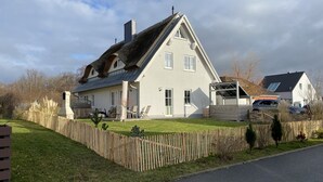 Una casa de dos pisos con techo inclinado, patio cercado y garaje.