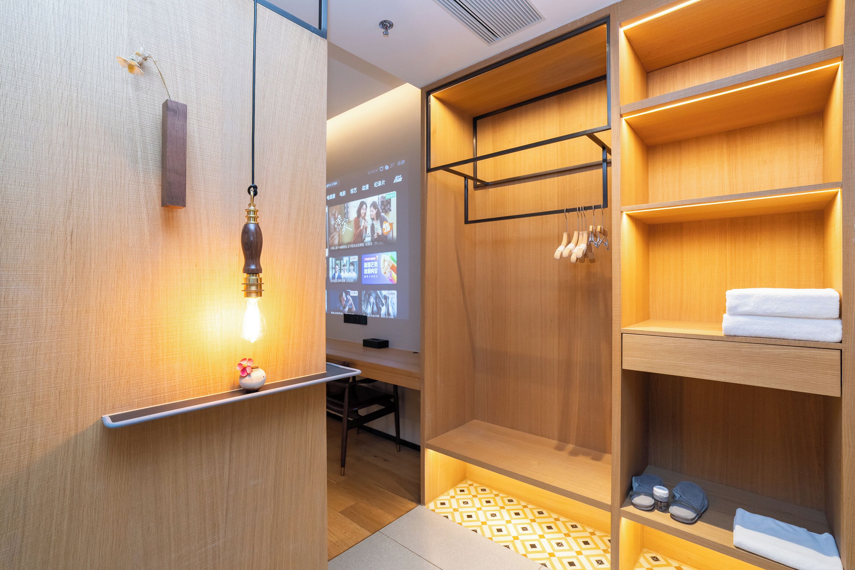 A modern bathroom with wooden shelving, a towel rack, and a projection screen displaying images.