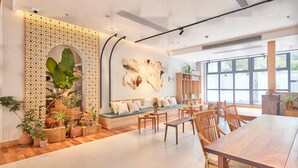 A modern interior with a wooden dining table, a seating area with cushions, and a bookshelf. - Yitel Hotel Shanghai ex Timeless Boutique House (Shanghai)