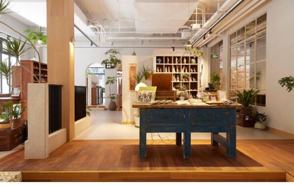 Una habitación amplia con piso de madera, una mesa azul y estantes con objetos decorativos.