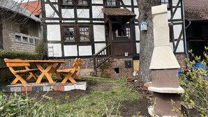 Una casa tradicional de entramado de madera con un banco de madera y una estructura de piedra en primer plano.