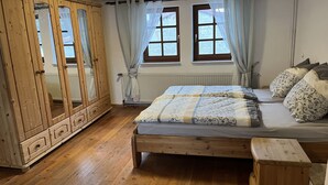 Un dormitorio con cama y armario de madera, y una ventana con cortinas.