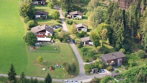 Une vue aérienne d’un quartier résidentiel avec plusieurs maisons, une aire de jeux et une route.