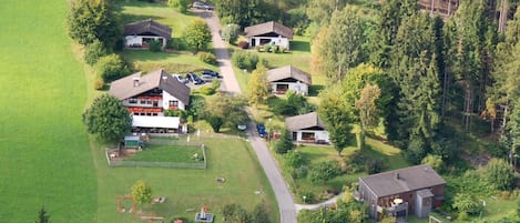 An aerial view of a residential area with multiple houses, a playground, and a road.