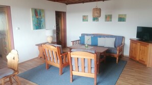 Un salon chaleureux avec une table à manger en bois, deux chaises, un canapé et un téléviseur.