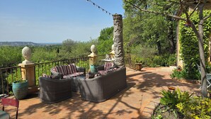 An outdoor seating area with wicker furniture, a decorative pillar, and a view of the landscape. - Air-conditioned luxury farmhouse, heated pool,sport hall, billiard table soccer, (Robion)
