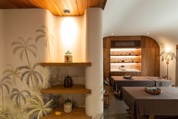 Una sala de spa con estantes de madera, una camilla de masaje y una pared con murales de palmeras.