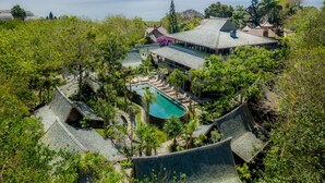 Un complexe hôtelier doté d’une architecture traditionnelle, d’une piscine et d’une végétation luxuriante.