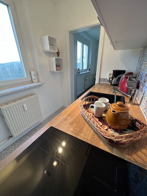Una cocina con encimera de madera, un radiador, una ventana y una puerta que da a otra habitación.