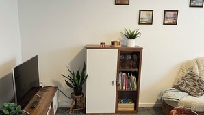 Een woonkamer met een televisie, een houten kast, een boekenkast en een bank.