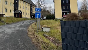 Een gebouw met een T-vormige entree, een parkeerbord en een lantaarnpaal.