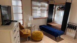 A compact living space with a sofa, ottoman, bench, TV, lamp, and a radiator. - Lily Pad by Paymán Club (Royston)