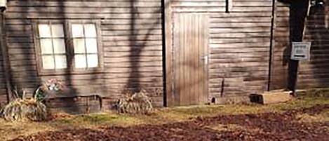 A rustic wooden building with a gabled roof, a wooden door, and a small window.